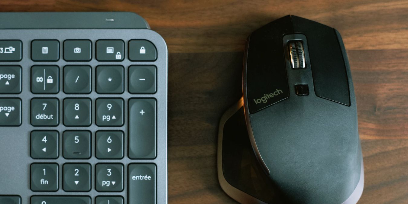 A mouse and keyboard set on a brown desk