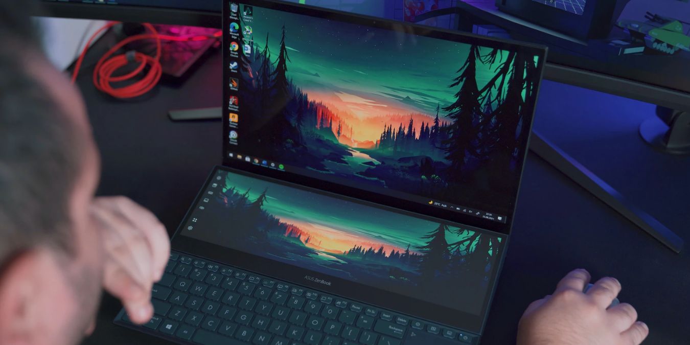 A dual-screen laptop showing intensive wallpaper graphics