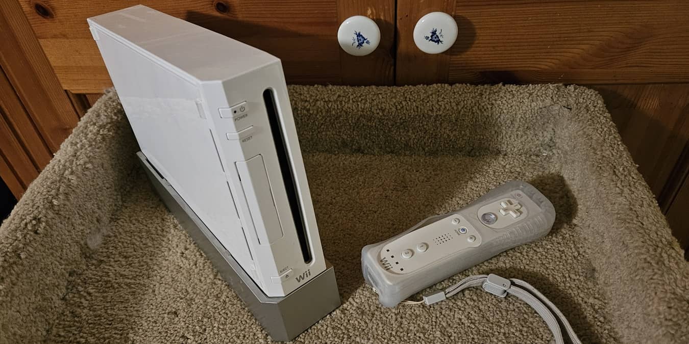 Nintendo Wii with controller sitting in front of a cabinet.