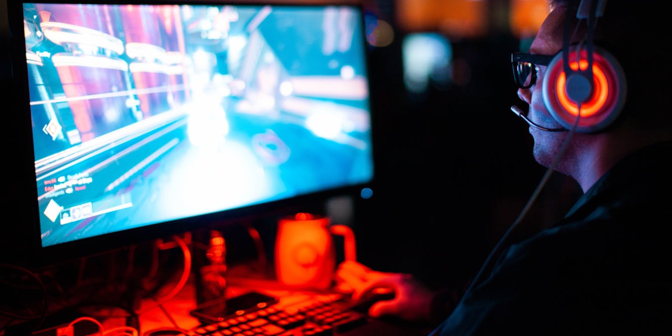 A photograph of a person playing a video game on a desktop PC.